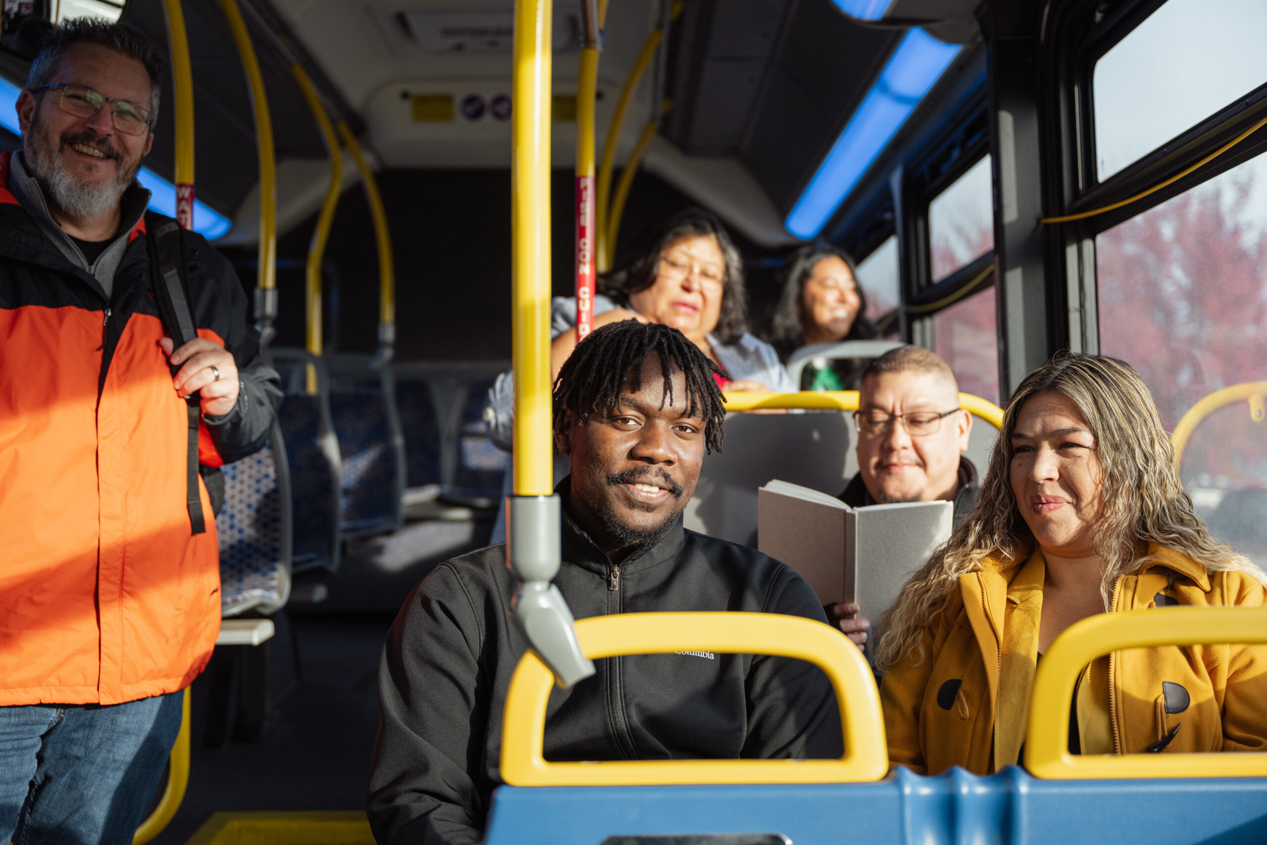Many people riding inside a bus, smiling.