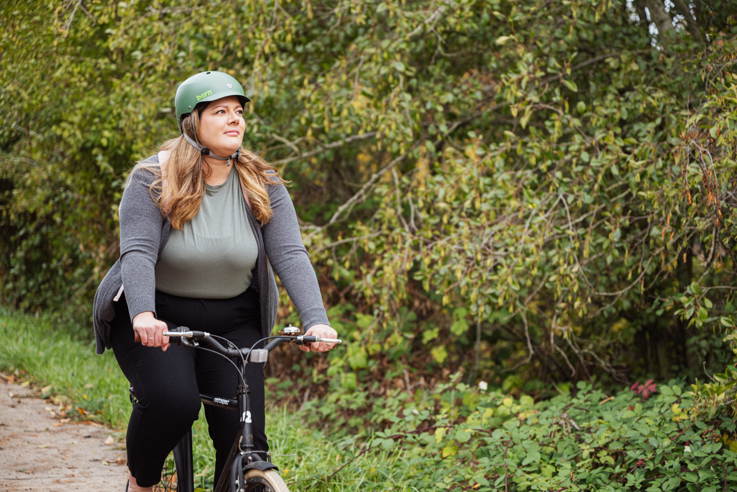 Woman biking on nature path and staring off into the trees.
