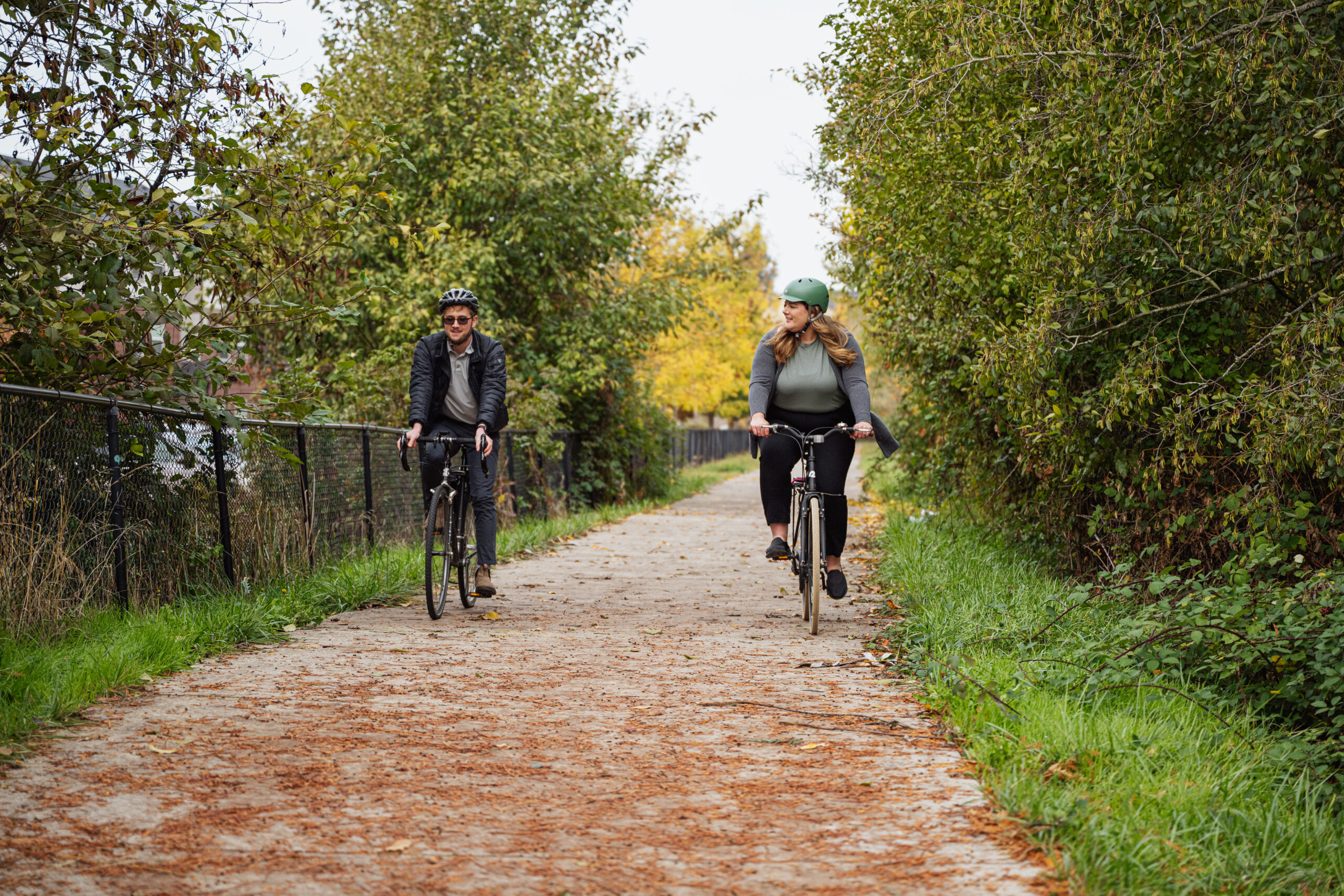 Two people biking next to each other along a paved trail.