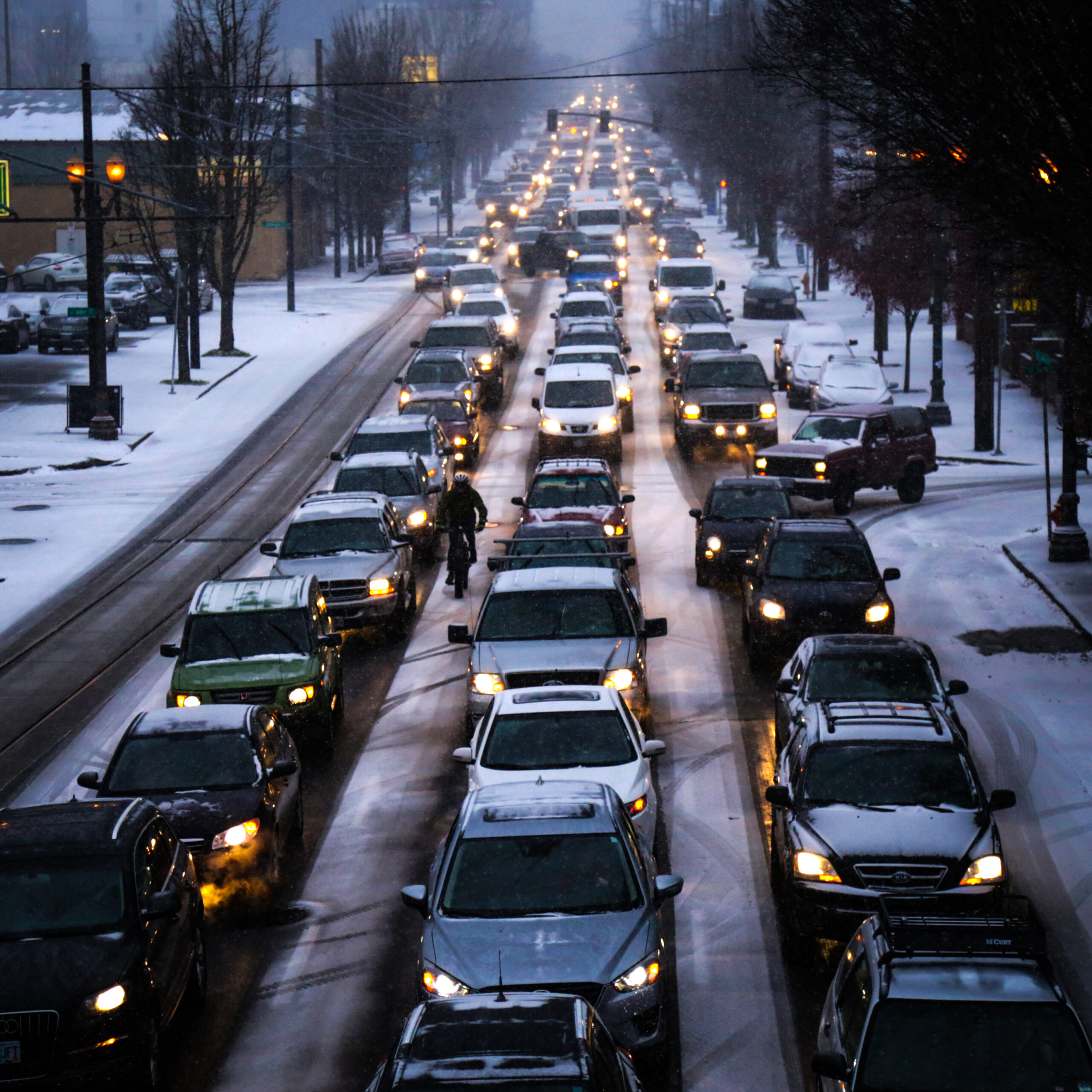 Three lanes of bumper-to-bumper cars on a snowy road.