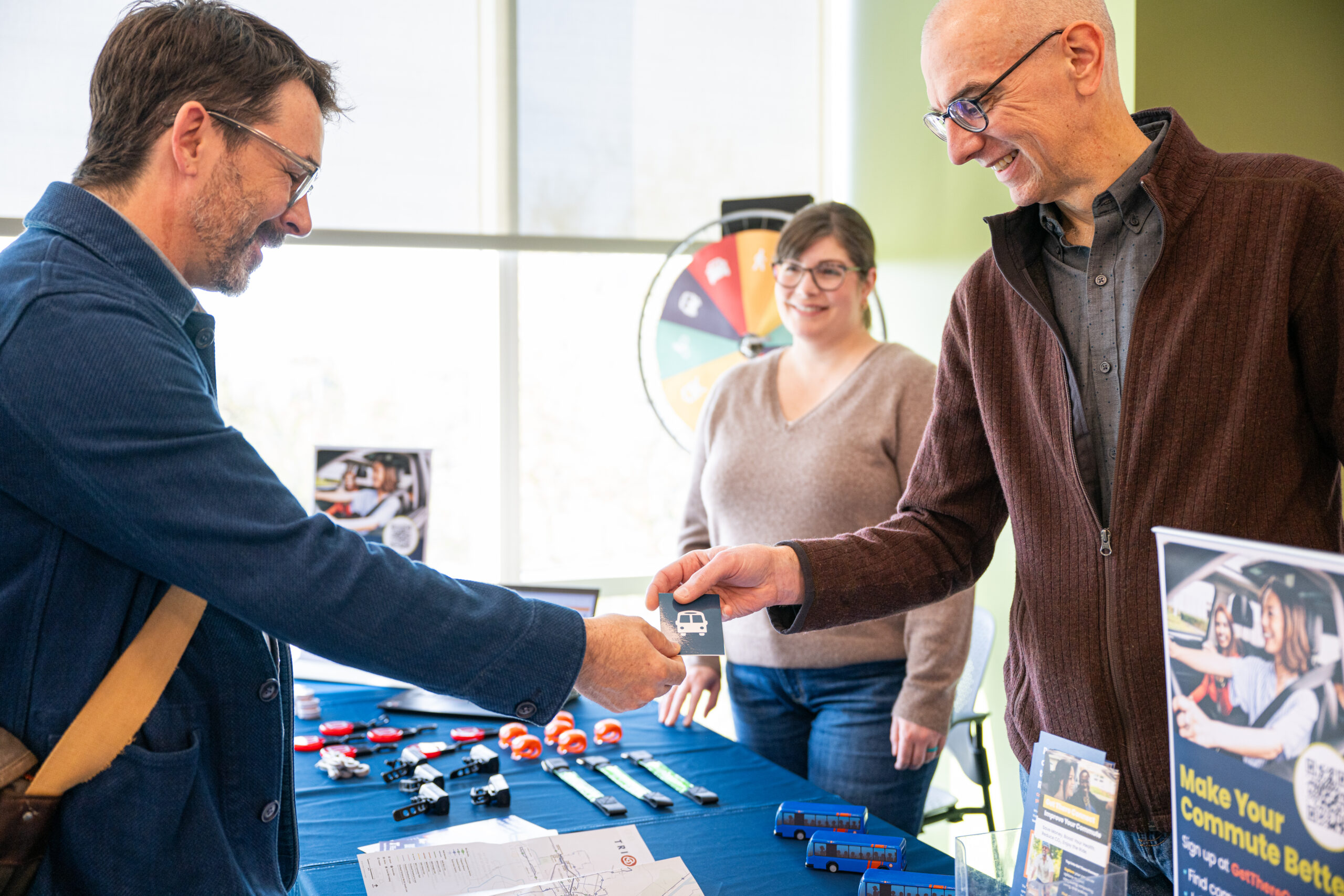 Person receiving a sticker from two people at a Get There tabling event.